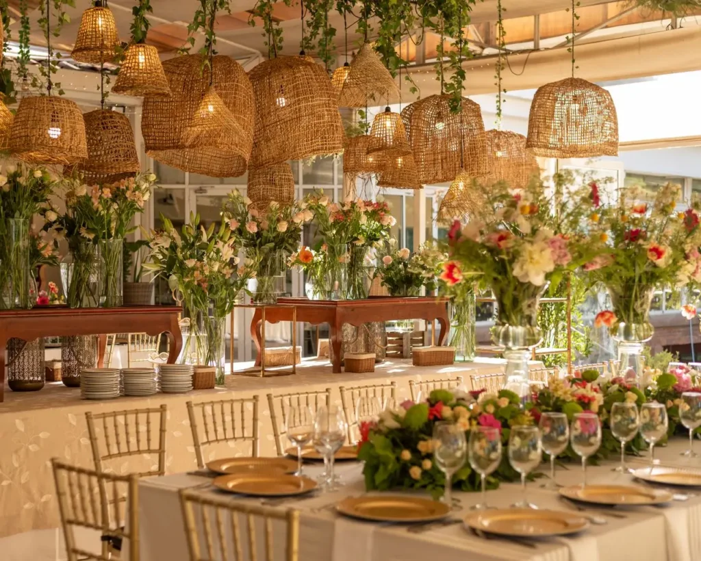 Beautifully decorated table with flowers and woven lamps for an elegant indoor event.